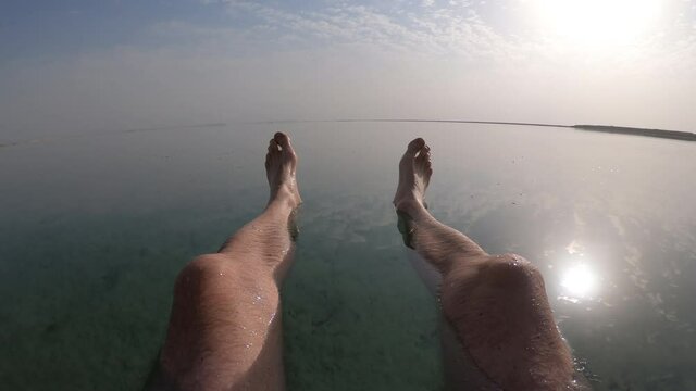 Holiday and recreation, point of view of man floating in the Dead Sea. Travel and tourism in Israel.
