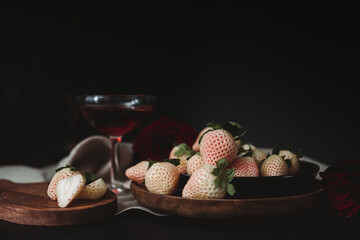 Moody Valentine Still Life. Pineberry on Wooden Plate with Dark Background. White Strawberry. Dark...