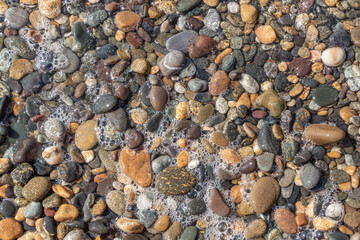 Beautiful texture of colorful smooth stones is on the beach by sea