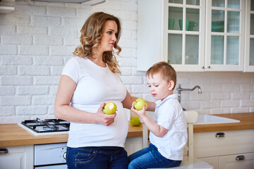 concept of healthy food. A pregnant woman and her little son are eating apples.