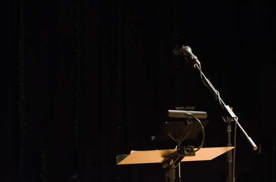 Music stand with microphone on a stage with a black background