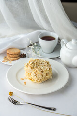 Whole cake decorated with almond flakes and cup of tea on the table