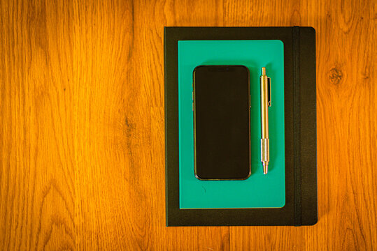 Cell phone and pen on notebook and journal