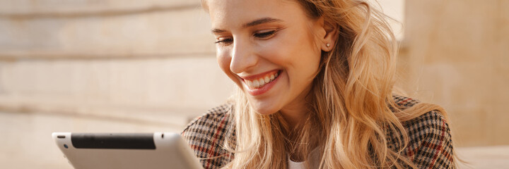 Smiling young blonde woman holding tablet