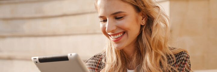 Smiling young blonde woman holding tablet