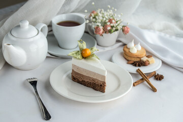 Slice of Triple Chocolate mousse Cake and cup of tea on the table
