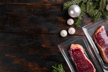 Raw steak with Christmas tree decorations, on old dark  wooden table background, top view flat lay,...