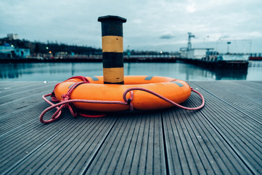 orange lifebuoy on the pier in the port in the evening