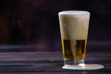 a large glass of cold light beer with foam on a dark background. St.Patrick 's Day