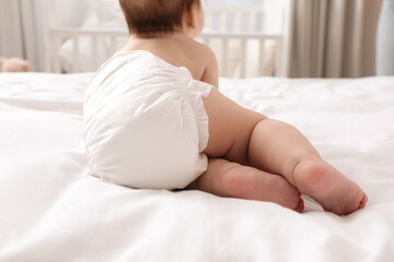 Fototapeta na wymiar Little baby in diaper on bed at home, back view
