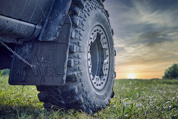 An off-road car splattered with mud against a beautiful sky. Car tire and mudguard 4x4. Off-road...