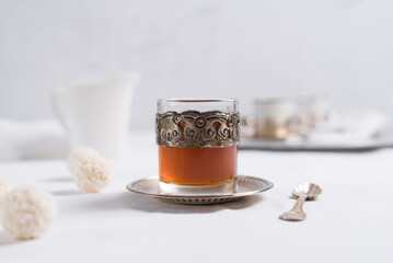 Un vaso de té clásico con dulces chocolates blancos cubiertos de coco en el cuadro blanco	