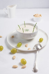 Crema de almendras, sopa fría española. Ajo blanco de Málaga con almendras y uvas en un recipiente blanco sobre una mesa blanca	