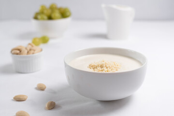 Crema de almendras, sopa fría española. Ajo blanco de Málaga con almendras y uvas en un recipiente blanco sobre una mesa blanca	