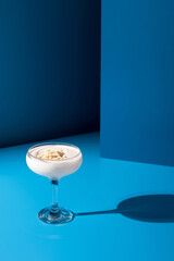 Crema de almendras, sopa española fría. Ajo blanco malagueño con almendras servido en un vaso  sobre  fondo azul