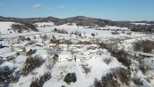 Gorgeous landscape view on a bright sunny cold winter day. Snow covered ground in the valley with residential neighborhood and farm. 