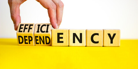 Efficiency or dependency symbol. Businessman turns cubes, changes the word dependency to efficiency. Beautiful yellow table, white background, copy space. Business, efficiency or dependency concept. - obrazy, fototapety, plakaty