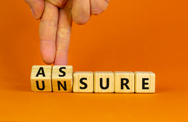 Assure or unsure symbol. Businessman turns wooden cubes and changes the concept word unsure to assure. Beautiful orange table, orange background, copy space. Business and assure or unsure concept.