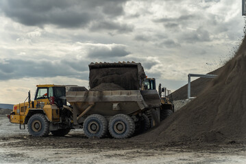 The loader loads an articulated dump truck. The action takes place near the filtration shop.	