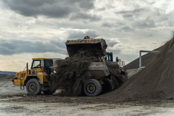 The loader loads the processed ore into an articulated dump truck. The action takes place near the filtration shop at the gold mine site.