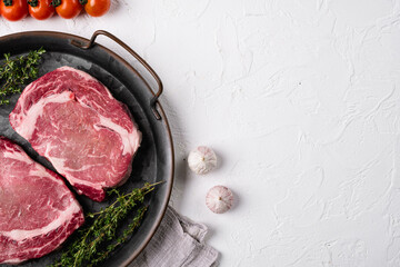 Perfect raw rib eye beef steak, on white stone table background, with copy space for text