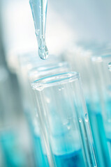 Close-up of a drop from a laboratory pipette dripping into a laboratory test tube. Medical research and development concept