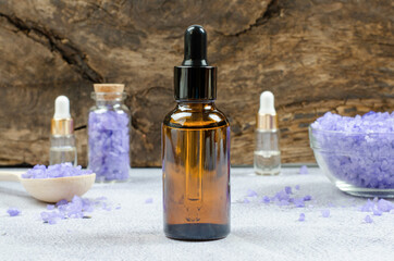 Beauty spa composition. A bottle of essential oil or serum on the background of a bowl of sea salt and oil bottles.