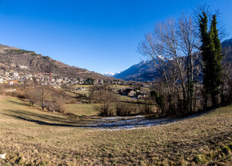 Obraz premium mountain agricultural landscape with overgrown green meadow in winter in a sunny day