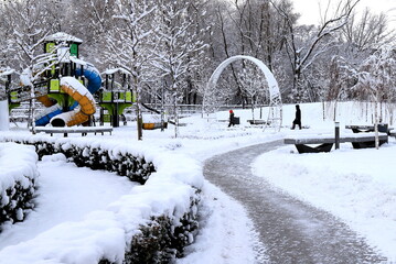 Winter park square street with children s playground, covered with snow. Children's slides and...