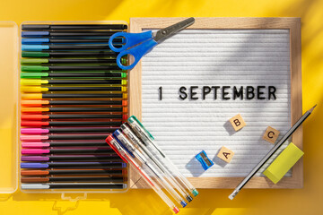 1 september letter board with school supplies as pens, scissors, ABC, paints on yellow background. Education. Knowledge day, study, back to school concept