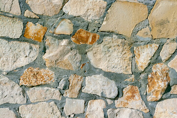 Stone wall texture. The texture of a stone wall made of ocher stones of various sizes and shapes.