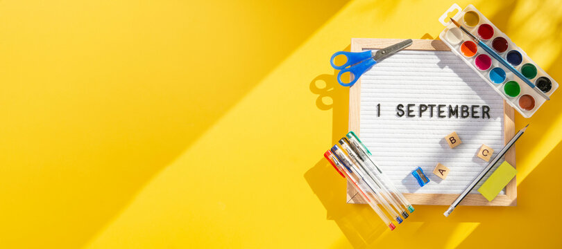 1 september letter board with school supplies as pens, scissors, ABC, paints on yellow background. Education. Knowledge day, study, back to school concept