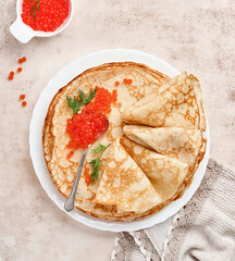 Crepes, thin pancakes, Russian pancakes with red caviar on gray plate. Marble background. Copy space. Top view