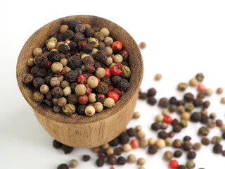 Peppercorns 4 colors in a wooden bowl and scattered on the table