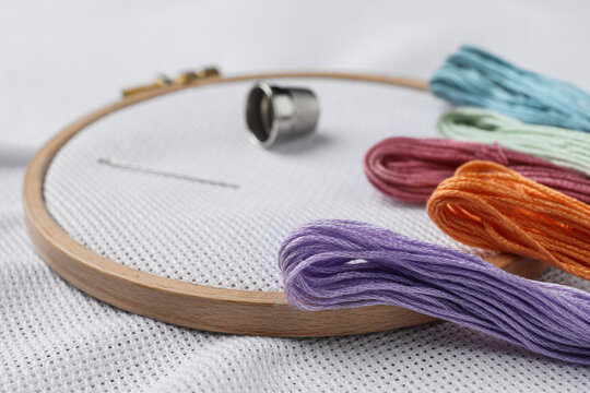 Threads and embroidery hoop with white fabric, closeup