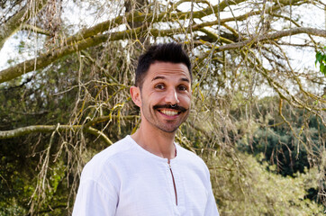 Young man with white shirt, mustache and nose piercing, posing smiling