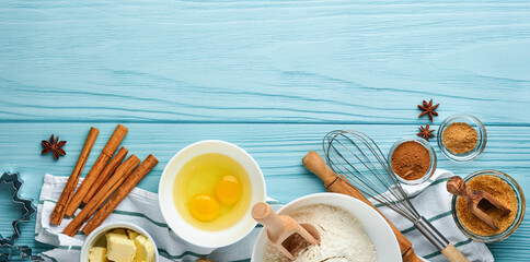 Baking background with ingredients for making gingerbread flour, eggs, kitchen tools, utensils and cookie molds on blue wooden table. Top view. Flat lay style. Mock up. Christmas baking.