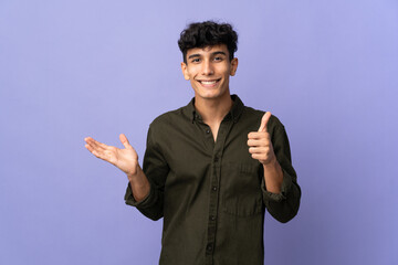 Young Argentinian man isolated on background holding copyspace imaginary on the palm to insert an...