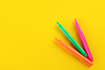 Colorful markers on yellow background, flat lay. Space for text