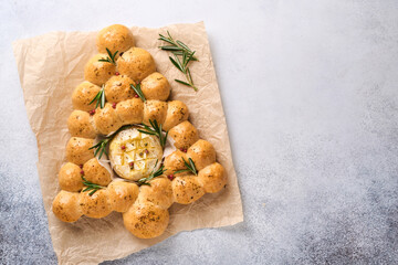 Bread buns Christmas tree with Roasted camembert cheese and rosemary on rustic background. Holiday recipes. Christmas menu. Christmas or Xmas pastries. Top view. Copy Space.