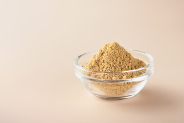 Flax fiber. Ground flaxseeds in glass bowl soluble fiber supplement for intestinal on a beige background. Superfood for healthy. Copy space, free space, space for text.