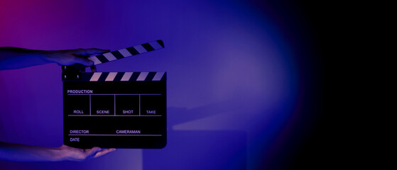 Blurry images of movie slate or clapper board. Hand holds empty film making clapperboard on color...