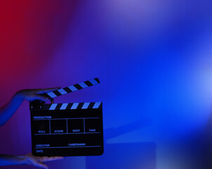 Blurry images of movie slate or clapper board. Hand holds empty film making clapperboard on color...