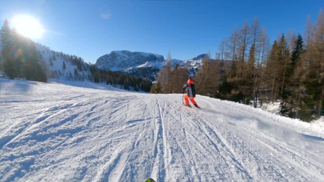 Man in colorful cloth skiing in the Nassfeld, Austria. Sunny weather in the mountains on a perfect groomed ski slope. Enjoying the slopes in a beautiful ski resort on a cold winter day. 