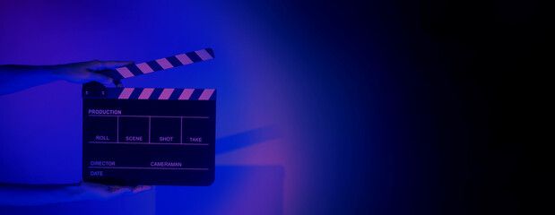 Blurry images of movie slate or clapper board. Hand holds empty film making clapperboard on color background in studio for film movie shooting or recording. Film slate for Youtuber video production.