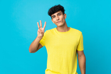 Young Argentinian man isolated on background happy and counting three with fingers