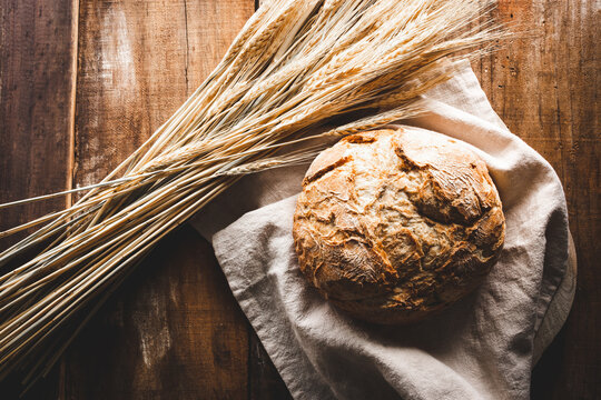 vista superior de una hogaza de pan con espigas de trigo sobre una mesa de madera r&uacute;stica