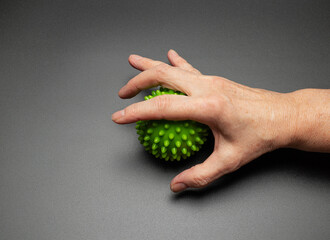 The hand of an elderly woman is squeezing a relief ball. Exercises for hands and fingers. Rehabilitation
