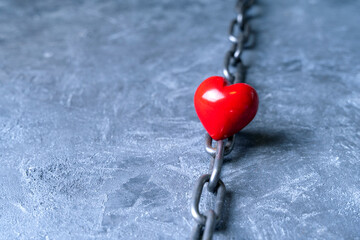 Difficult love relationship concept with a heart symbol and metal chain.