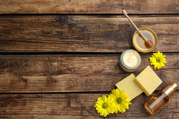 Flat lay composition with beeswax and cosmetic products on wooden table. Space for text